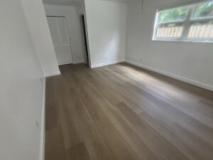 Completed bedroom flooring, install installation with modern-look final plate and white baseboard in Delray Beach